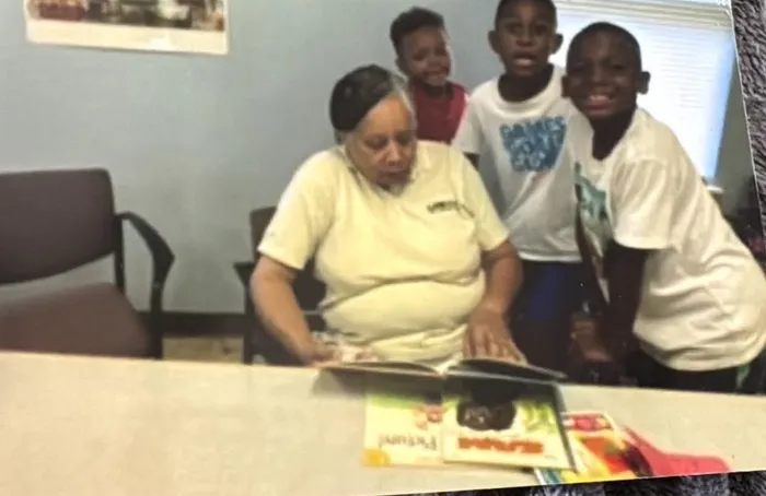 A mentor reads a picture book with a small group of youth